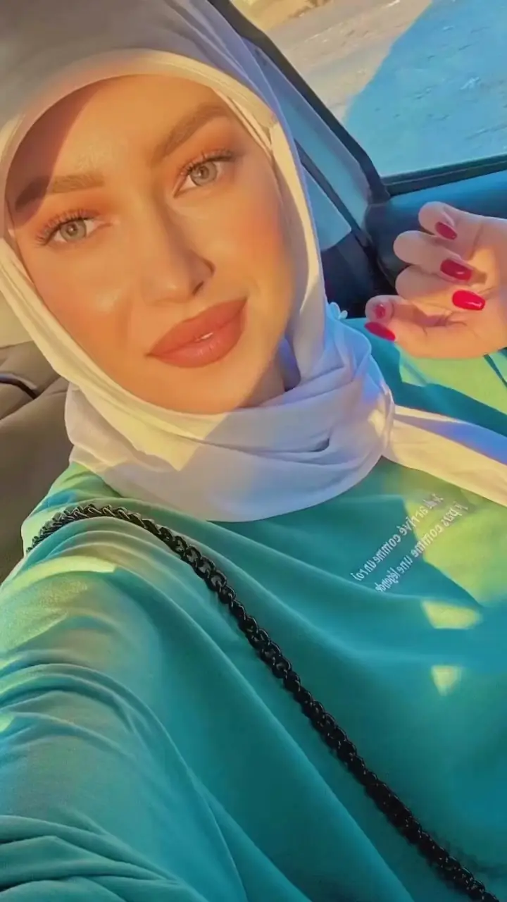 Woman in a headscarf smiling into her phone camera
